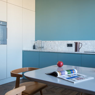 Foto di una cucina lineare contemporanea di medie dimensioni con ante lisce, ante blu, paraspruzzi blu, pavimento in legno massello medio, nessuna isola, pavimento marrone, top grigio e top alla veneziana