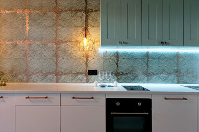 ノボシビルスクにある低価格の小さなインダストリアルスタイルのおしゃれなキッチン (フラットパネル扉のキャビネット、白いキャビネット、ガラス板のキッチンパネル、ラミネートの床、白い床) の写真