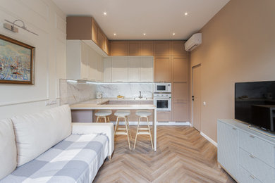 Идея дизайна: угловая кухня-гостиная в современном стиле с фасадами в стиле шейкер, бежевыми фасадами, белым фартуком, белой техникой, полуостровом, бежевым полом и белой столешницей