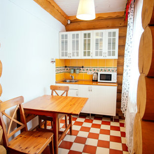 Modelo de cocina comedor lineal, retro, pequeña, con fregadero encastrado, armarios tipo vitrina, puertas de armario blancas, salpicadero naranja, salpicadero de azulejos de cerámica, suelo de baldosas de cerámica y encimeras naranjas