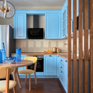 Foto de cocina comedor en L, escandinava, de tamaño medio, con fregadero encastrado, armarios con paneles con relieve, puertas de armario turquesas, encimera de laminado, salpicadero beige, salpicadero de azulejos de cerámica, electrodomésticos de acero inoxidable, suelo de madera oscura, suelo marrón y encimeras marrones