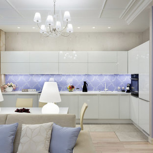 Inspiration for a mid-sized contemporary l-shaped open plan kitchen in Saint Petersburg with an integrated sink, flat-panel cabinets, white cabinets, glass sheet splashback, black appliances, no island, solid surface benchtops, multi-coloured splashback, ceramic floors, grey floor and white benchtop.