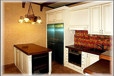 Стильный дизайн: угловая кухня среднего размера в классическом стиле с обеденным столом, врезной мойкой, фасадами с выступающей филенкой, белыми фасадами, деревянной столешницей, разноцветным фартуком, фартуком из керамической плитки, черной техникой, полом из керамической плитки, островом, коричневым полом и коричневой столешницей - последний тренд