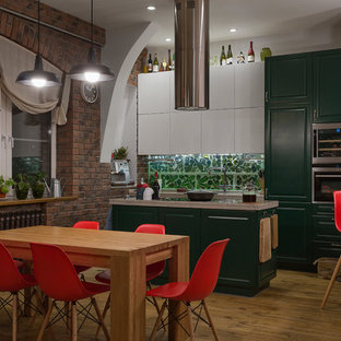 This is an example of an industrial eat-in kitchen in Moscow with raised-panel cabinets, green cabinets, green splashback, stainless steel appliances, medium hardwood floors and with island.
