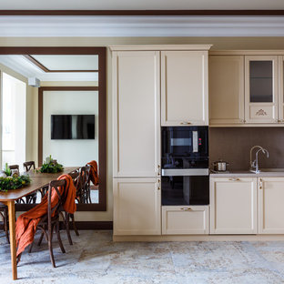 Design ideas for a transitional u-shaped open plan kitchen in Other with a drop-in sink, shaker cabinets, beige cabinets, grey splashback, black appliances and a peninsula.