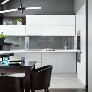 Design ideas for a mid-sized contemporary l-shaped open plan kitchen in Moscow with an integrated sink, flat-panel cabinets, white cabinets, solid surface benchtops, grey splashback, glass tile splashback, black appliances, porcelain floors, no island, grey floor and white benchtop.