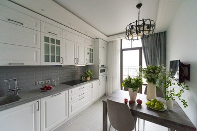 На фото: маленькая угловая кухня в стиле неоклассика (современная классика) с фасадами с утопленной филенкой, белыми фасадами и серым полом для на участке и в саду с