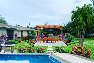 Imagen de camino de jardín tropical grande en patio trasero con jardín francés, exposición total al sol y adoquines de ladrillo