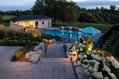 This is an example of a large contemporary partial sun backyard stone landscaping in Toronto for summer.