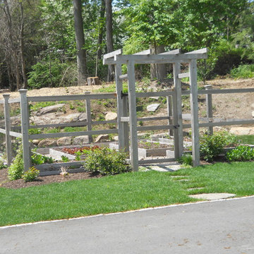 A fenced vegetable garden with an arbor is located in the front yard. Stepping s