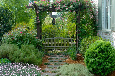 Foto de jardín tradicional de tamaño medio en verano en patio trasero con adoquines de piedra natural y jardín francés