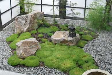 На фото: маленький садовый фонтан на внутреннем дворе в восточном стиле с покрытием из гравия для на участке и в саду