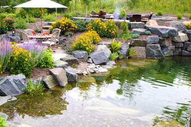This is an example of a large traditional full sun backyard water fountain landscape in Minneapolis for summer.