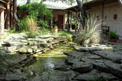 Diseño de jardín mediterráneo de tamaño medio en patio trasero con jardín francés, fuente, exposición parcial al sol y adoquines de piedra natural