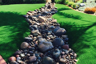 Design ideas for a mid-sized traditional drought-tolerant and partial sun front yard river rock landscaping in San Diego.