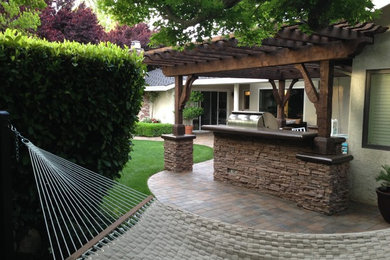 Imagen de jardín clásico de tamaño medio en patio trasero con exposición parcial al sol y adoquines de ladrillo