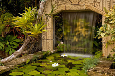Modelo de jardín tropical pequeño en patio con fuente, exposición parcial al sol y adoquines de piedra natural