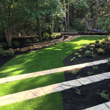 Artificial turf with terraced steps, dry creek bed and shade tolerant plants.