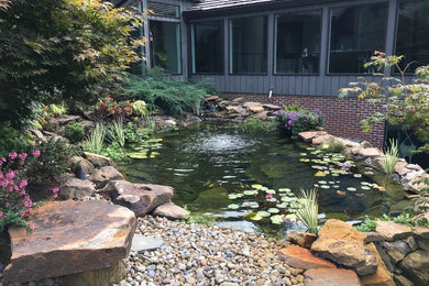 Medium sized bohemian sloped garden in Cleveland with a pond and gravel.