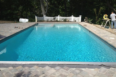 Modelo de piscina clásica grande en patio trasero con adoquines de hormigón