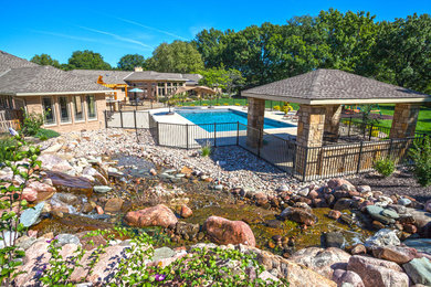 Photo of a mid-sized modern partial sun backyard stone pond in Kansas City for summer.
