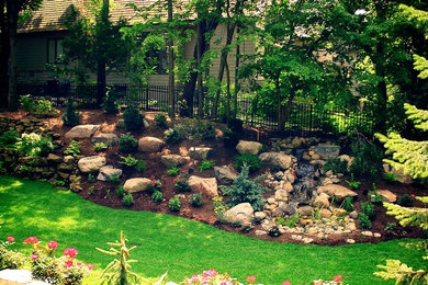 Großer, Halbschattiger Rustikaler Garten im Sommer, hinter dem Haus mit Mulch und Wasserspiel in Minneapolis
