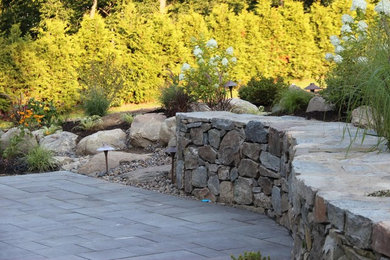 This is an example of a mid-sized traditional drought-tolerant and partial sun backyard concrete paver retaining wall landscape in New York for spring.