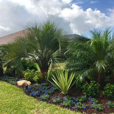 Design ideas for a mid-sized tropical partial sun backyard mulch formal garden in Orlando.