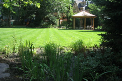 Modelo de jardín rústico de tamaño medio en verano en patio trasero con exposición parcial al sol y mantillo