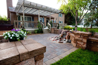 Large transitional backyard stone patio photo in Other