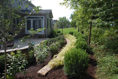 Diseño de jardín tradicional renovado en patio trasero con muro de contención, exposición parcial al sol y adoquines de piedra natural