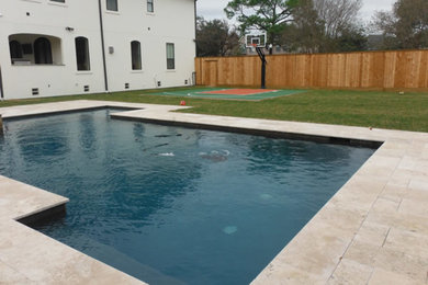 Example of a large classic backyard stone pool design in Houston