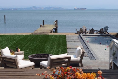 Aménagement d'un jardin arrière bord de mer avec un foyer extérieur et une terrasse en bois.