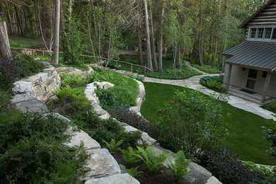 Пример оригинального дизайна: большой летний участок и сад на переднем дворе в стиле рустика с полуденной тенью, покрытием из каменной брусчатки и подпорной стенкой