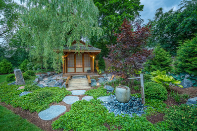 This is an example of a large asian partial sun backyard stone landscaping in Milwaukee.