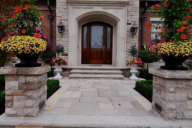 This is an example of a large traditional full sun front yard stone formal garden in Toronto.