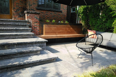 Modelo de jardín minimalista de tamaño medio en patio delantero con muro de contención, exposición total al sol y adoquines de piedra natural