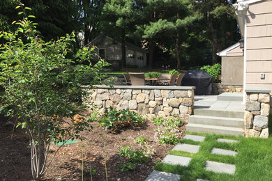 Photo of a mid-sized transitional partial sun side yard stone retaining wall landscape in Boston for spring.