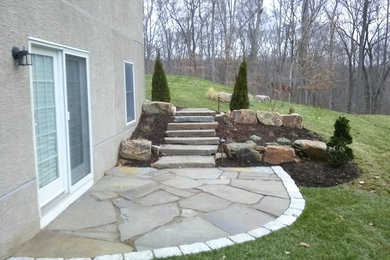 Diseño de jardín clásico grande en patio trasero con muro de contención, exposición total al sol y adoquines de piedra natural