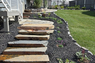 Photo of a large rustic full sun backyard stone landscaping in Edmonton for summer.