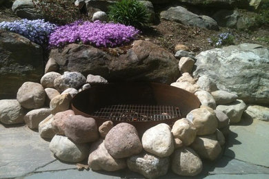 Inspiration for a traditional stone landscaping in New York with a fire pit.