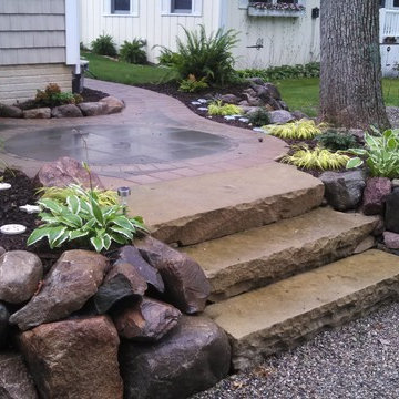 boulder walls and shade plantings surrounding sandstone steps with bluestone/bri