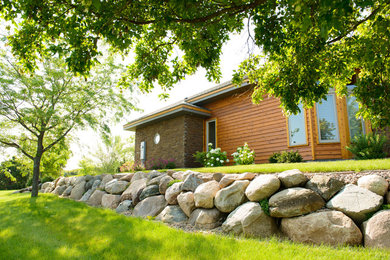 This is an example of a large traditional hillside stone retaining wall landscape in Other for summer.