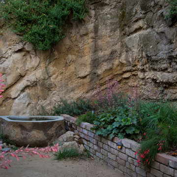 Boulder water feature, native and low water plantings, brick retaining wall with