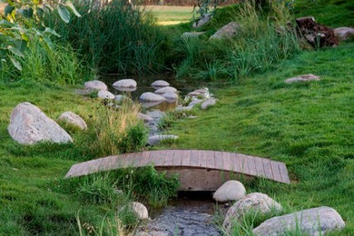 Design ideas for a mid-sized rustic hillside water fountain landscape in Other.