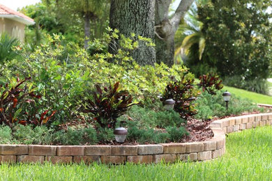This is an example of a small transitional partial sun front yard brick retaining wall landscape in Orlando.