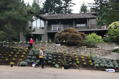 This is an example of a mid-sized mid-century modern drought-tolerant and full sun backyard gravel retaining wall landscape in Portland.