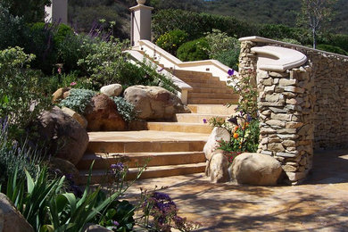 Imagen de jardín mediterráneo grande en ladera con exposición parcial al sol y adoquines de piedra natural