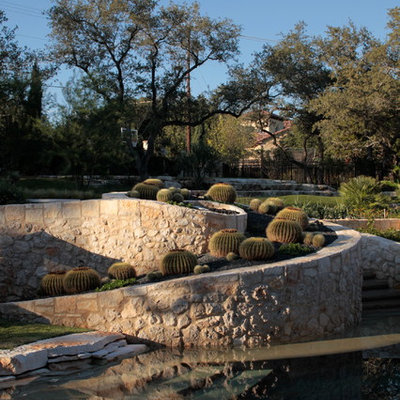 Photo of a mediterranean backyard retaining wall landscape in Austin.