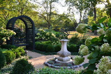 Imagen de camino de jardín clásico en patio trasero con gravilla, jardín francés y exposición parcial al sol
